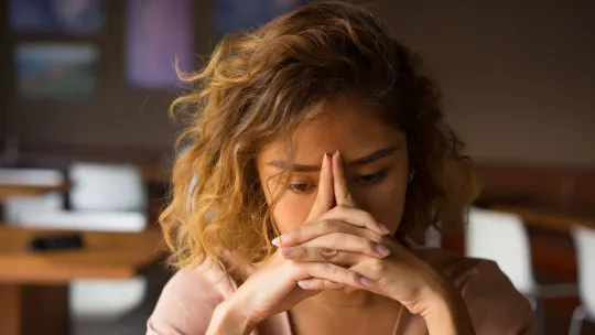 Frustrated woman with hands to her forehead.