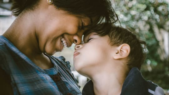 Mother holds child and they touch foreheads in loving gesture