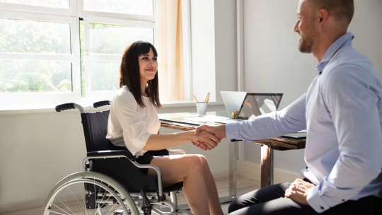 Woman in wheelchair working with man