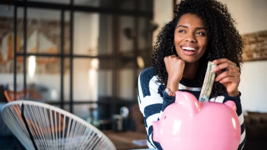 woman putting money in piggy bank