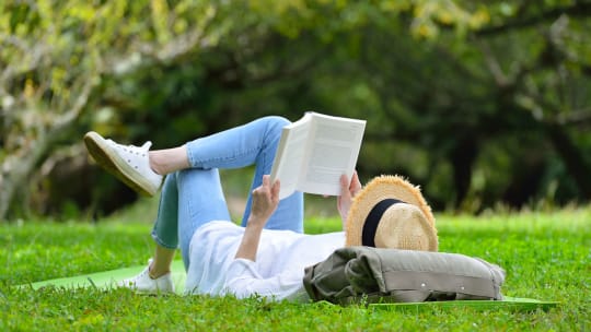 woman playing hooky from work reading in the park