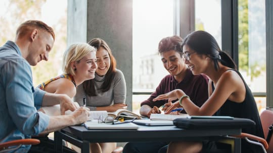 group of students sitting at a table in college