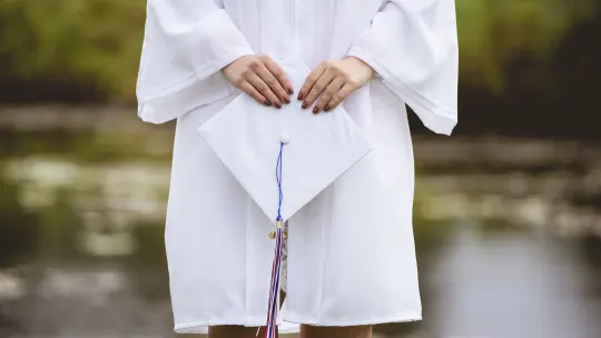 graduate in cap and gown raising her fist in the air