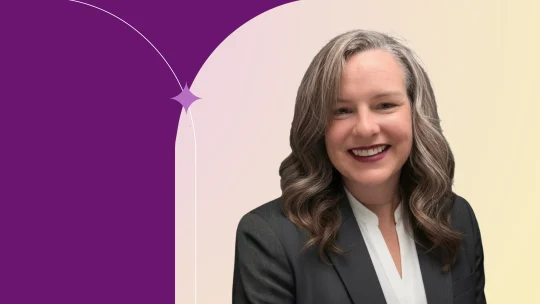 Nicole standing wearing a black jacket with white shirt, similling.