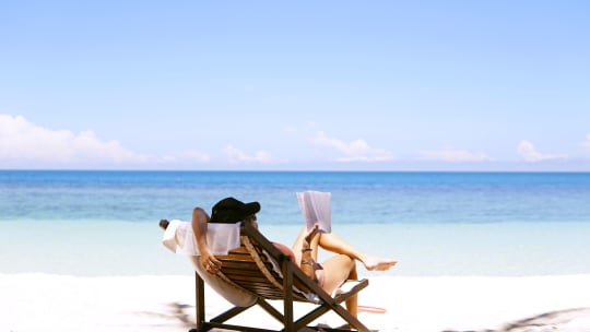 Woman on chair at beach, holding book