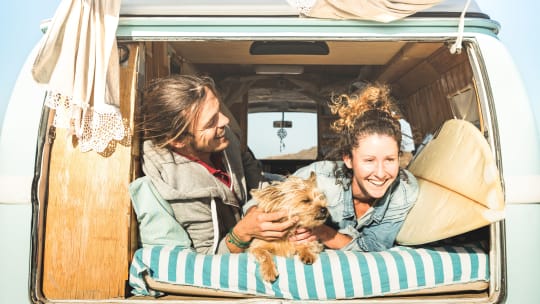 couple cuddling with a dog in the back of a van