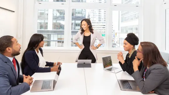 woman standing at the head of a table in a meeting
