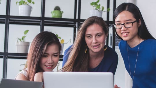 three young women looking at a computer