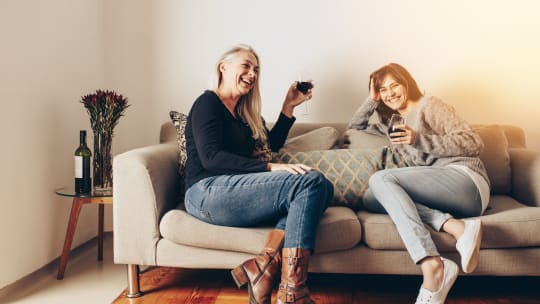 Two women sitting on a couch sharing a laugh