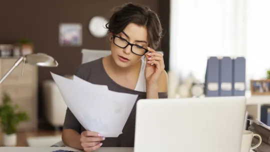woman reading papers at her desk