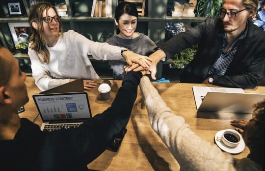 team of employees with hands in 