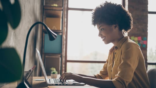 young woman typing on a laptop at her desk