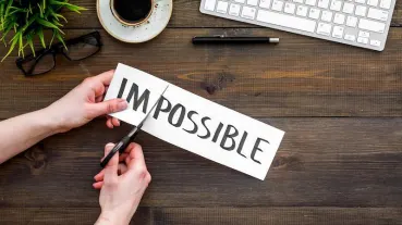 Cutting a paper that says "impossible" into "possible".