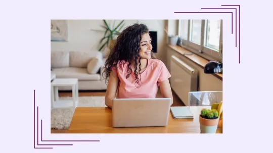 a woman smiling and looking at a laptop.
