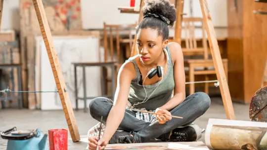 artist sitting on the floor working on a painting