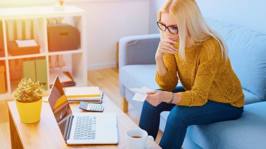A woman sits at a table paying bills