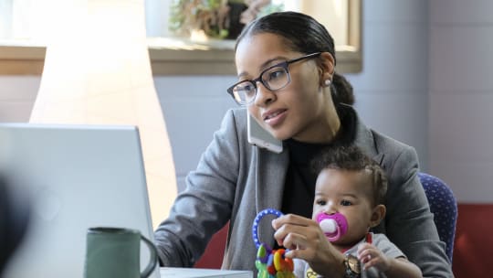 mother working from home with her daughter in her lap