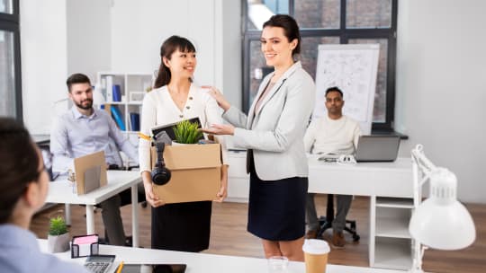 new employee carrying a box of her possession to her desk