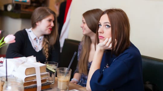 woman feeling isolated while coworkers gossip