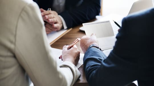 man and woman with pens and paper getting ready to sign documents