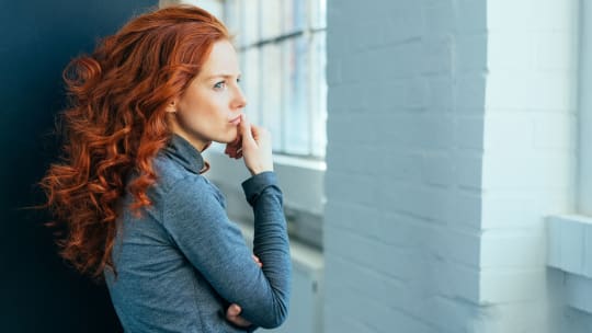 woman standing by a window thinking