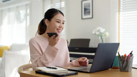 Woman talking on her cellphone while looking at laptop.