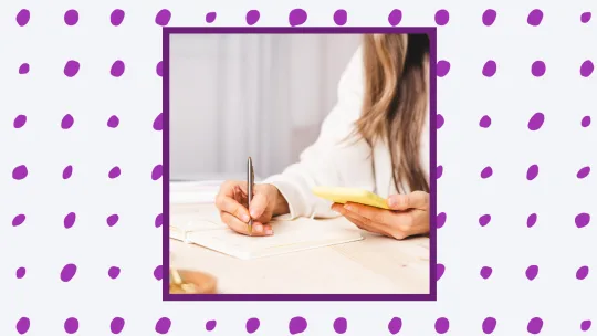 a woman writing on a sticky note. 