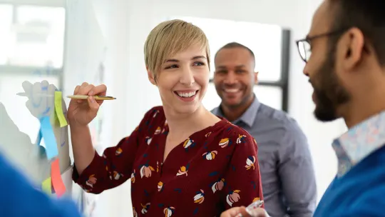 Portrait of a blonde short hair woman leading a diverse team of creative millennial coworkers in a startup brainstorming ideas