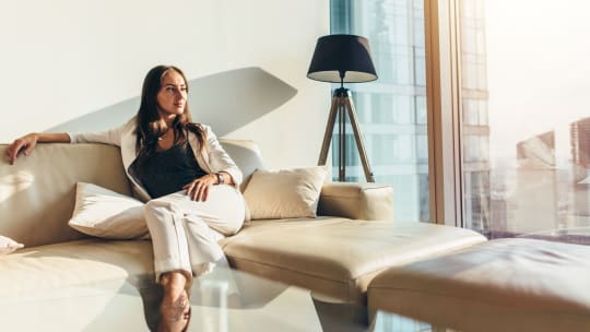 woman staring outside the window of a lavish apartment