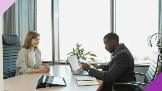 A woman looking excited while interviewing for a job, illustrating that you should aplly for jobs that require more experience