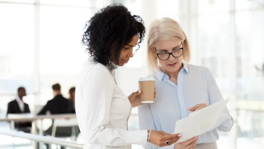 younger and older colleagues looking at a report and chatting