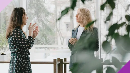 Two middle aged women at an office to illustrate how can menopause and work affect each other and the importance of learning coping strategies