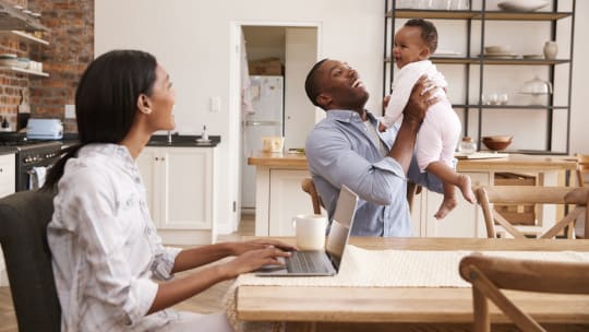 woman typing with a baby on her lap while she's on the phone