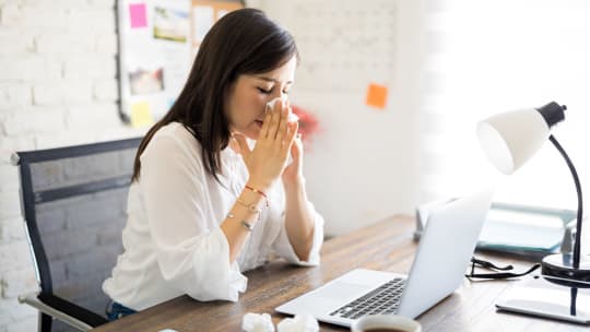 woman blowing her nose at work