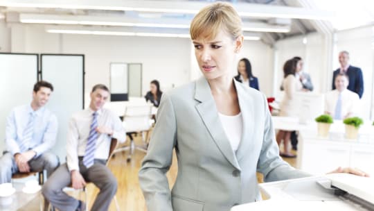 woman looking uncomfortable as men look on at work