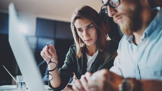Woman advising man on computer