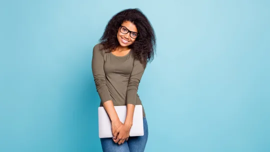 Woman holding laptop wearing jeans