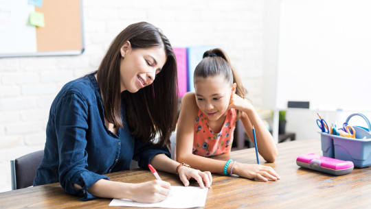 child and mother at a table homeschooling