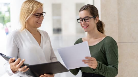 two women looking through a packet of papers