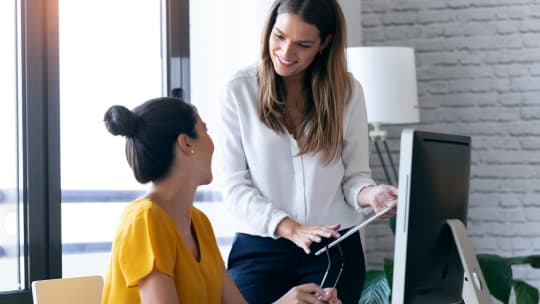 Two women talking at desk