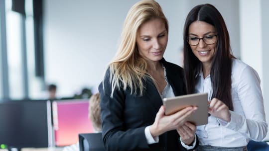 two women at work looking at tablet  