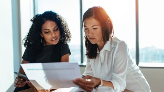 manager helping out employee on desk laptop