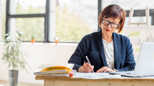 older woman writing in a sunlit room