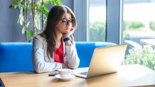 woman moping in front of laptop in cafe