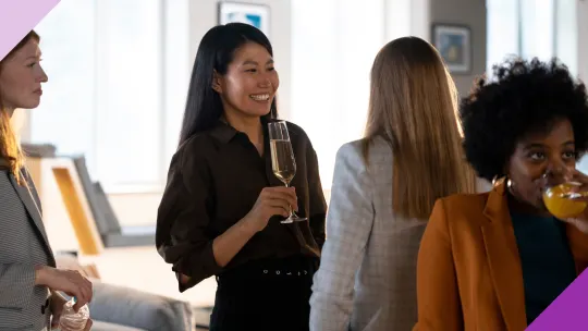 Four women networking at a professional event to illustrate the importance of building a network to further your career