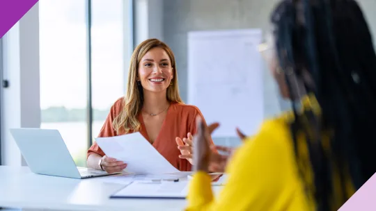 Two professionals in an office setting, one holding a paper, illustrating key skills to put on a resume