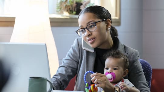 mom holding baby while working