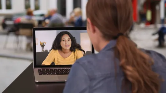 two women at work having a conversation via video vall