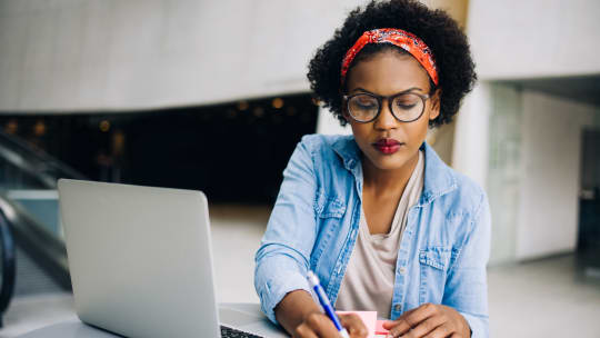 woman reading blog and taking notes