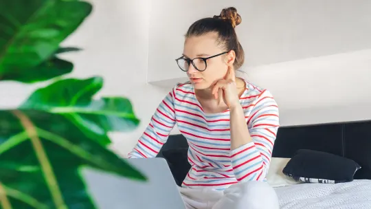 woman working at computer from bed